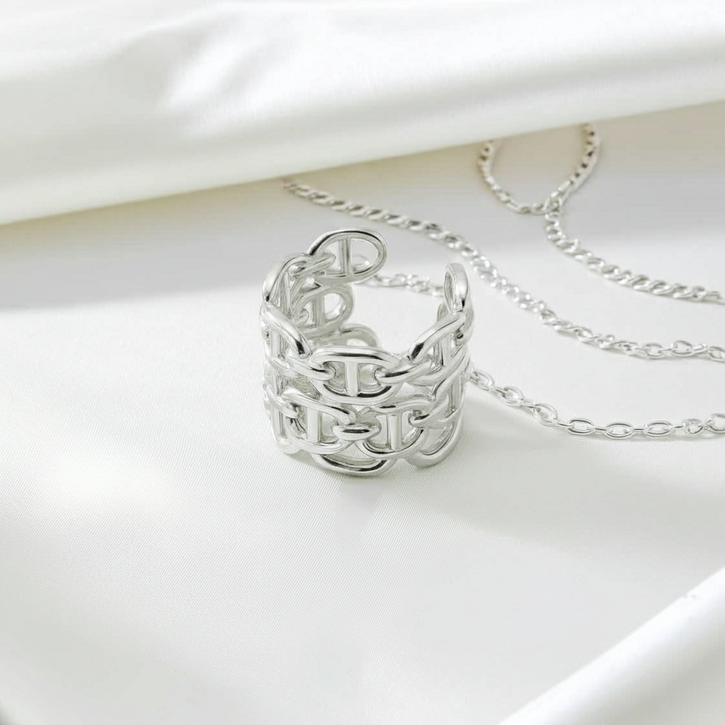Silver ring with engraved letters and matching necklace on a white background