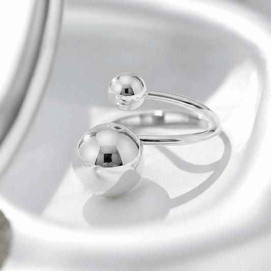 Silver ring with spherical elements on a reflective surface