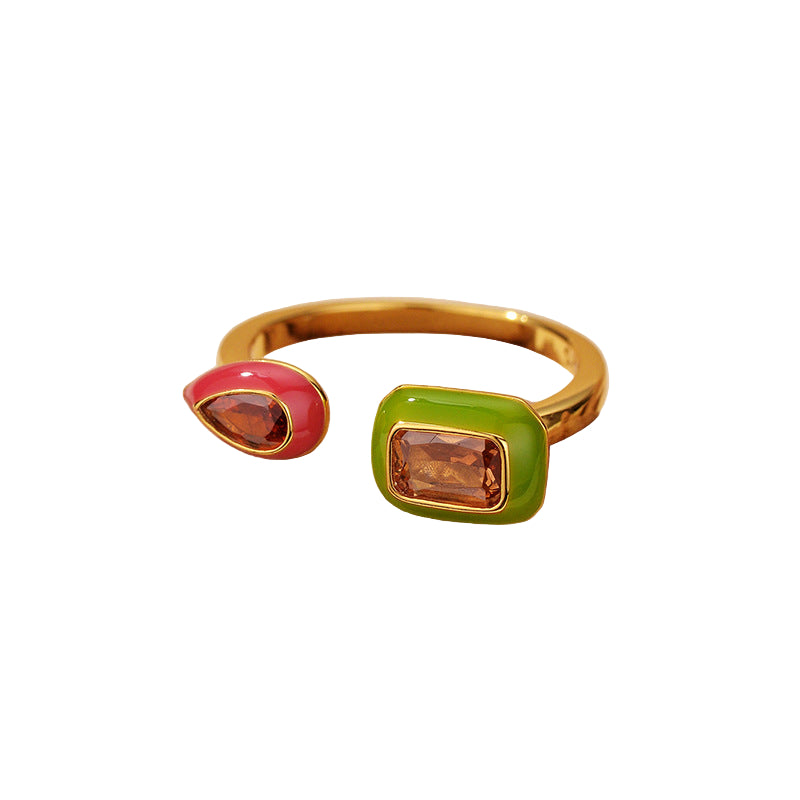 Gold ring with red and green gemstones on a white background