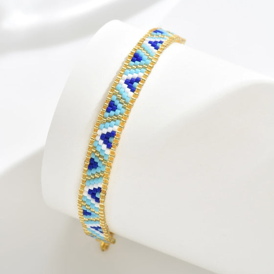 Beaded bracelet with blue and gold pattern on a white background