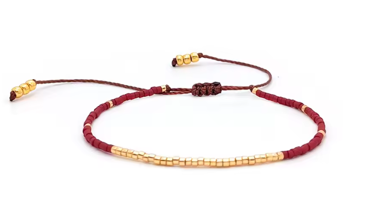 Bracelet with red and gold beads on a white background