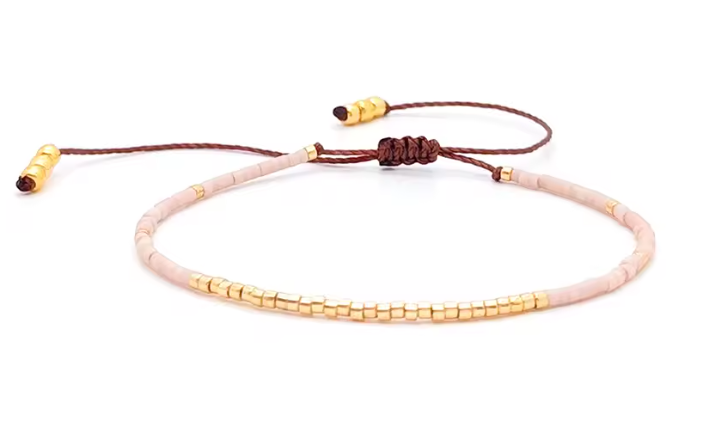 Bracelet with pink beads and gold accents on a white background