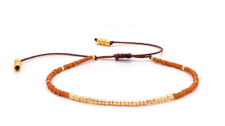 Bracelet with orange beads and gold clasps on a white background