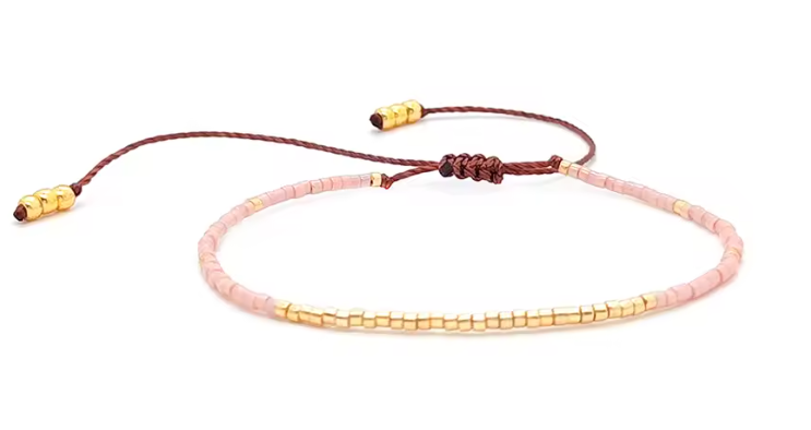 Bracelet with pink beads and gold accents on a white background