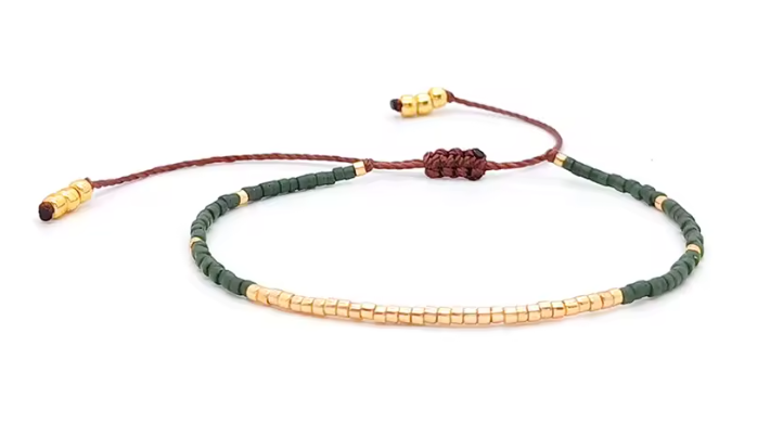 Bracelet with green and gold beads on a white background