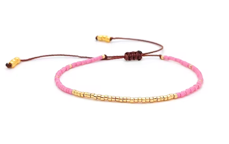 Bracelet with pink beads and gold accents on a white background