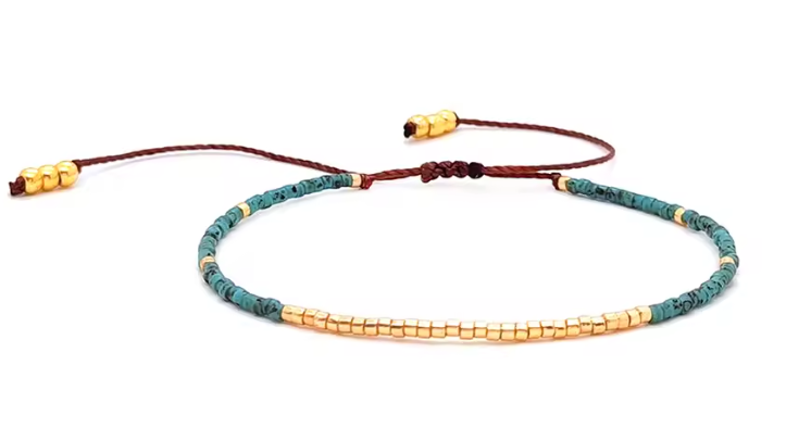 Bracelet with green and gold beads on a white background