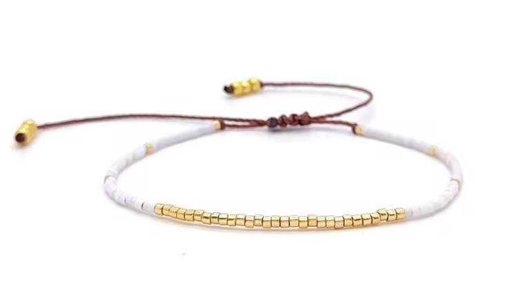 Bracelet with white beads and gold accents on a white background