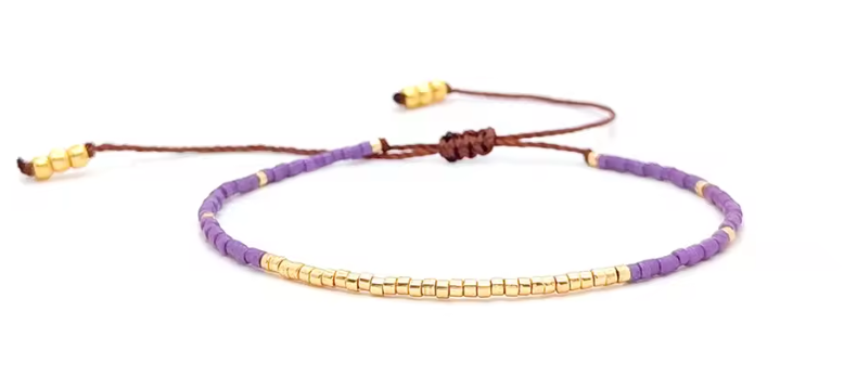 Purple beaded bracelet with gold accents on a white background