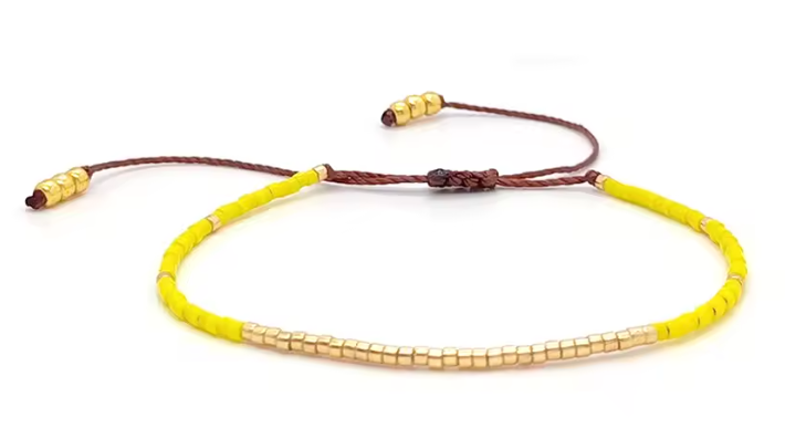 Bracelet with yellow beads and brown cord on a white background