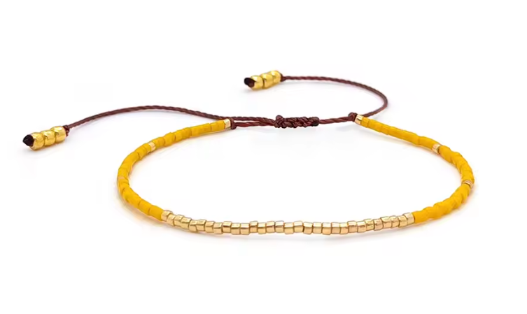 Yellow beaded bracelet with brown cord on a white background