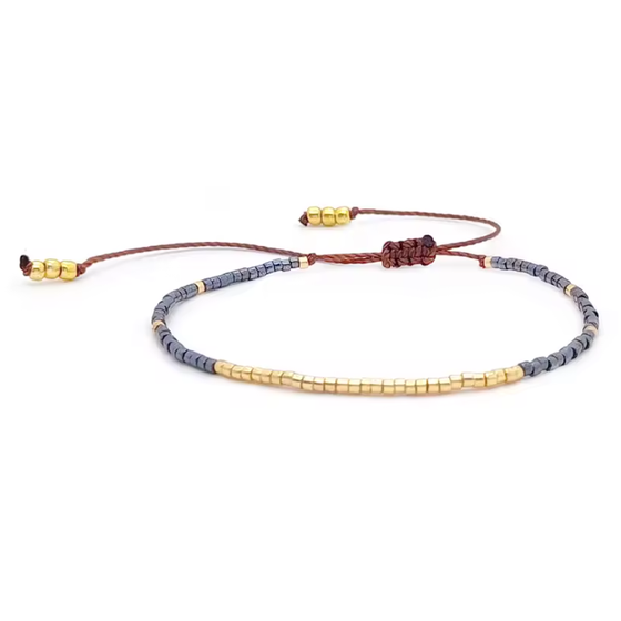 Bracelet with gold and gray beads on a white background