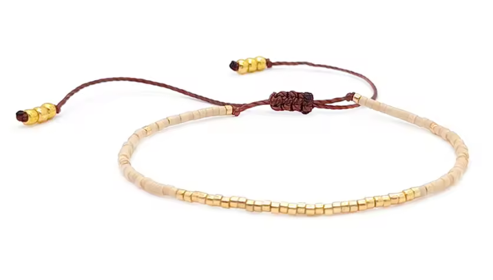 Necklace with gold beads and brown cord on a white background