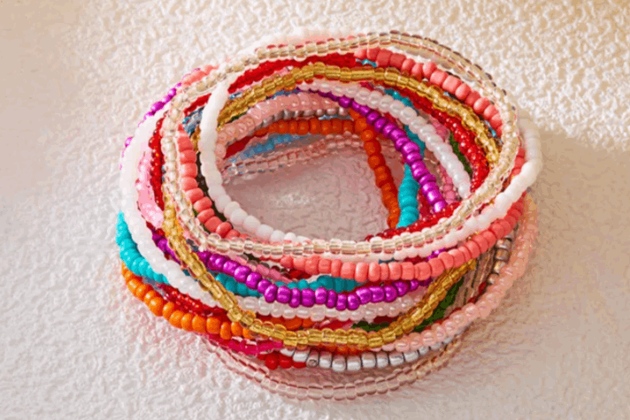 Stack of colorful beaded bracelets on a white surface