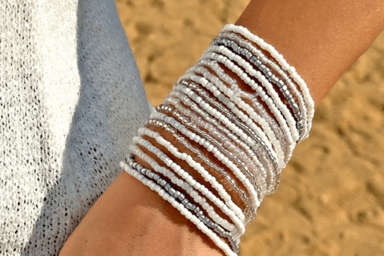 Close-up of a wrist wearing multiple beaded bracelets with a blurred natural background