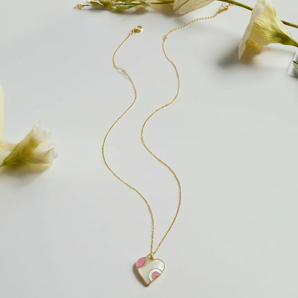 Gold necklace with a heart-shaped pendant on a light gray background with flowers.