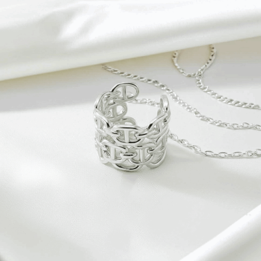 Silver ring with engraved letters and matching necklace on a white background