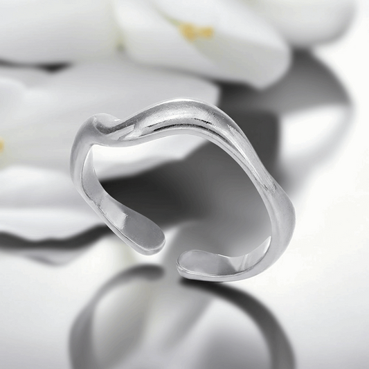 Silver ring with a wavy design on a reflective surface