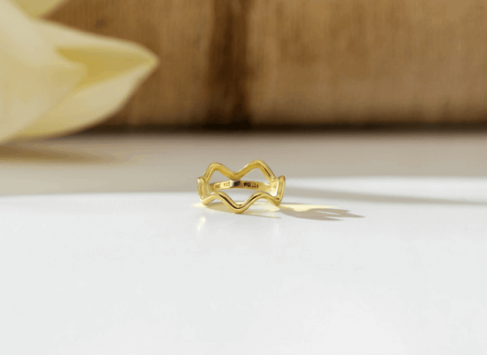 Gold ring on a white surface with a blurred wooden background