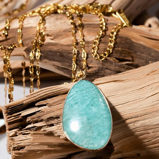 Gold necklace with a turquoise pendant on wooden background