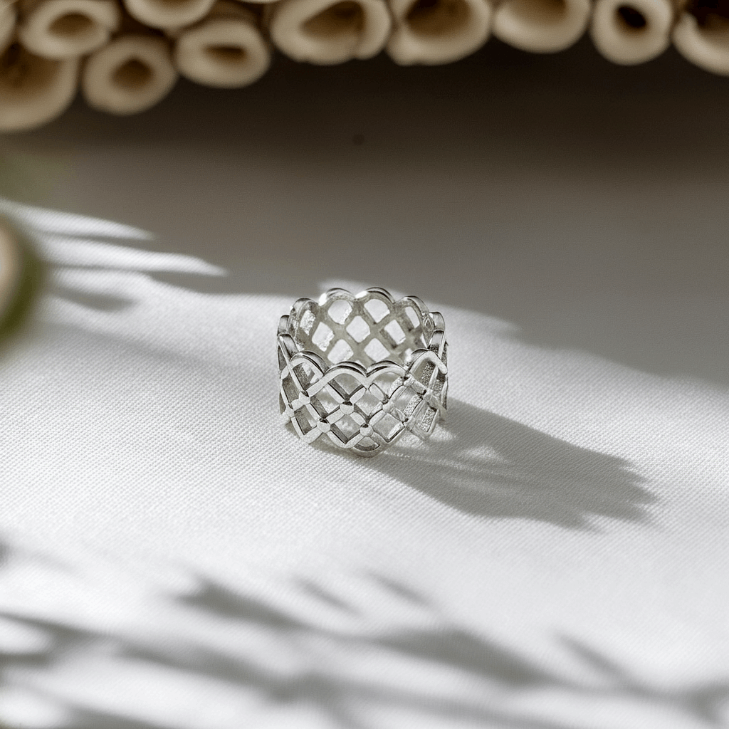 Silver woven ring on a light fabric background with natural light casting shadows