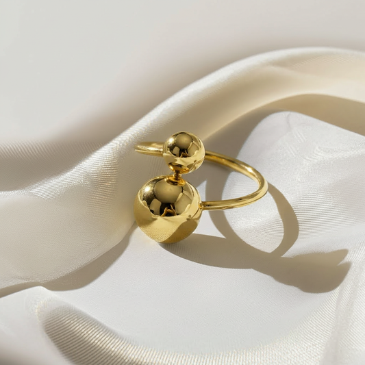 Gold ring with spherical design on a white fabric background