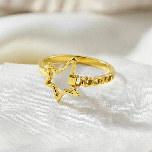 Gold ring with star design on a white fabric background