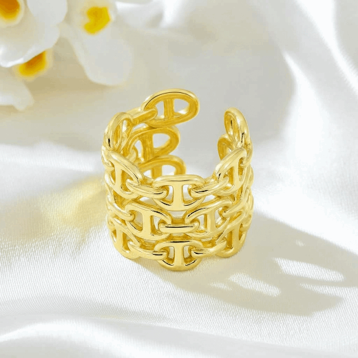 Gold chain-style ring on a white fabric background with flowers