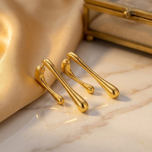 Gold earrings on a marble surface with a gold box in the background