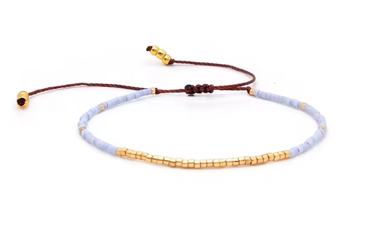 Bracelet with gold and light blue beads on a white background
