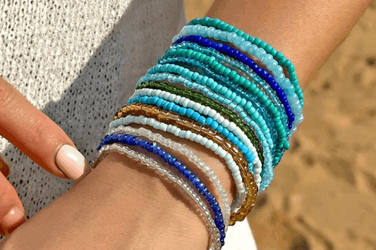 Multicolored beaded bracelets on a wrist with a blurred beach background