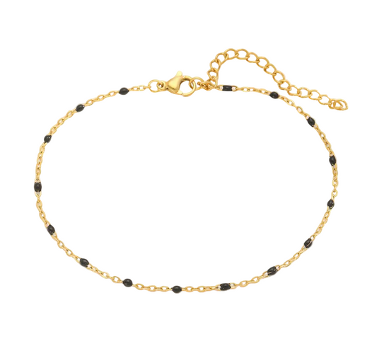 Gold bracelet with black beads on a light background