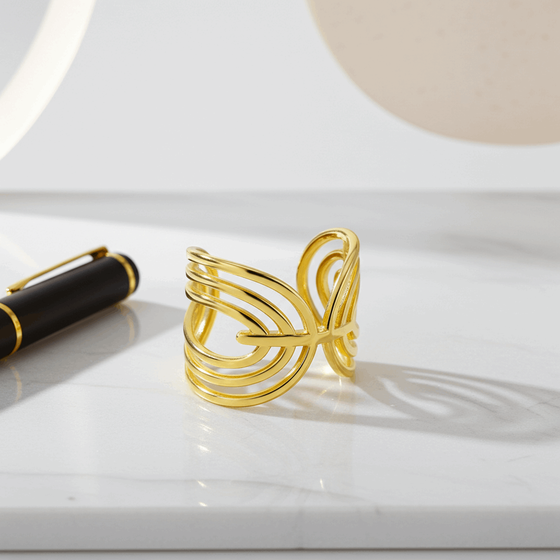 Gold openwork ring on a white surface with a pen