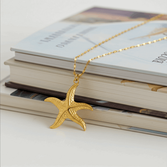 Gold starfish pendant necklace on a stack of books