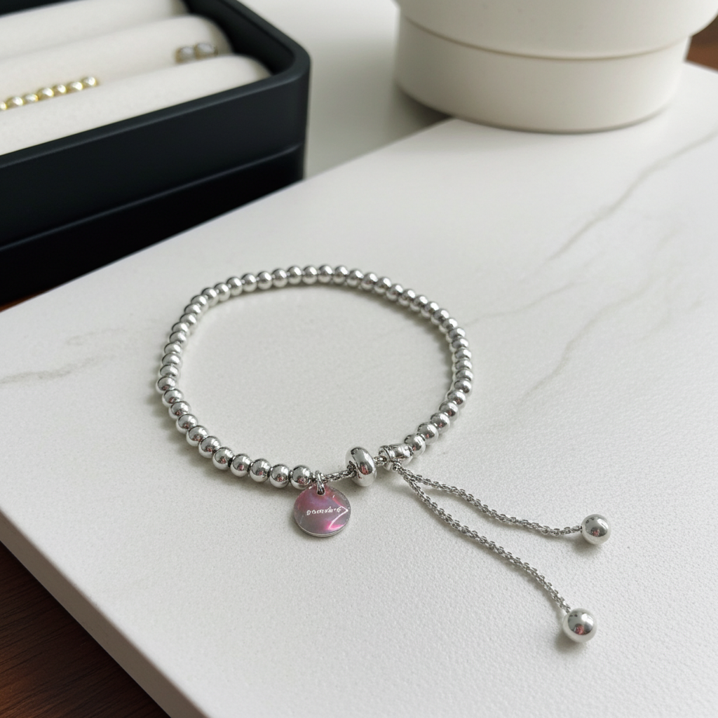 Silver bracelet with a silver round-shaped charm on a white surface