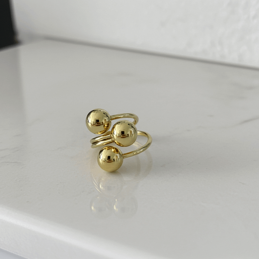 Gold ring with three spherical beads on a white background