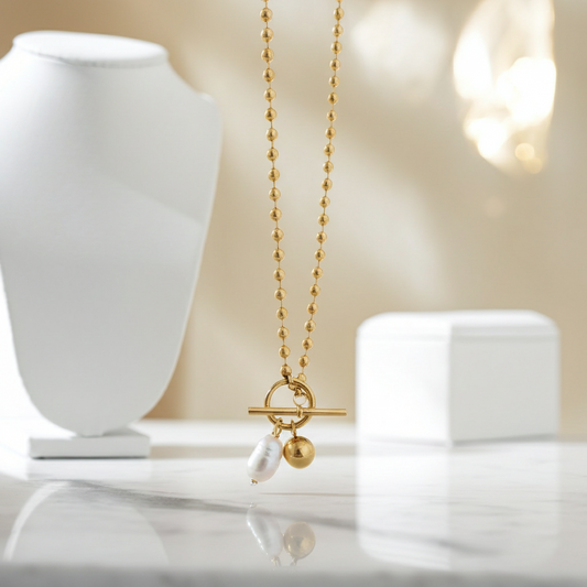 Gold necklace with a pearl pendant on a white surface