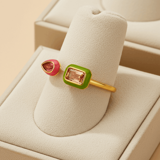 Gold ring with pink and green gemstones on a beige cushion