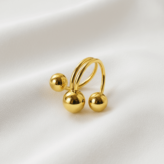 Gold ring with three spherical ends on a white background